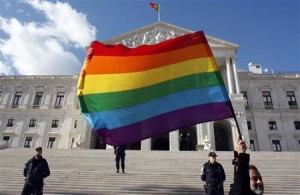 Man holds a rainbow flag in front of Portuguese Parliament after bill was passed to legalise same-sex marriages in Lisbon